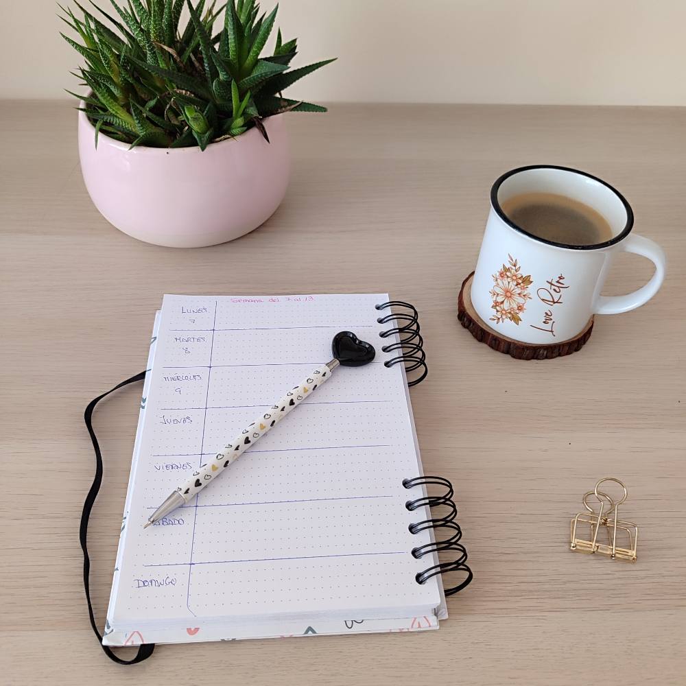 Espacio de trabajo relajado con una libreta Annacrea abierta y una taza de café, reflejando un ambiente creativo y equilibrado para la planificación diaria.